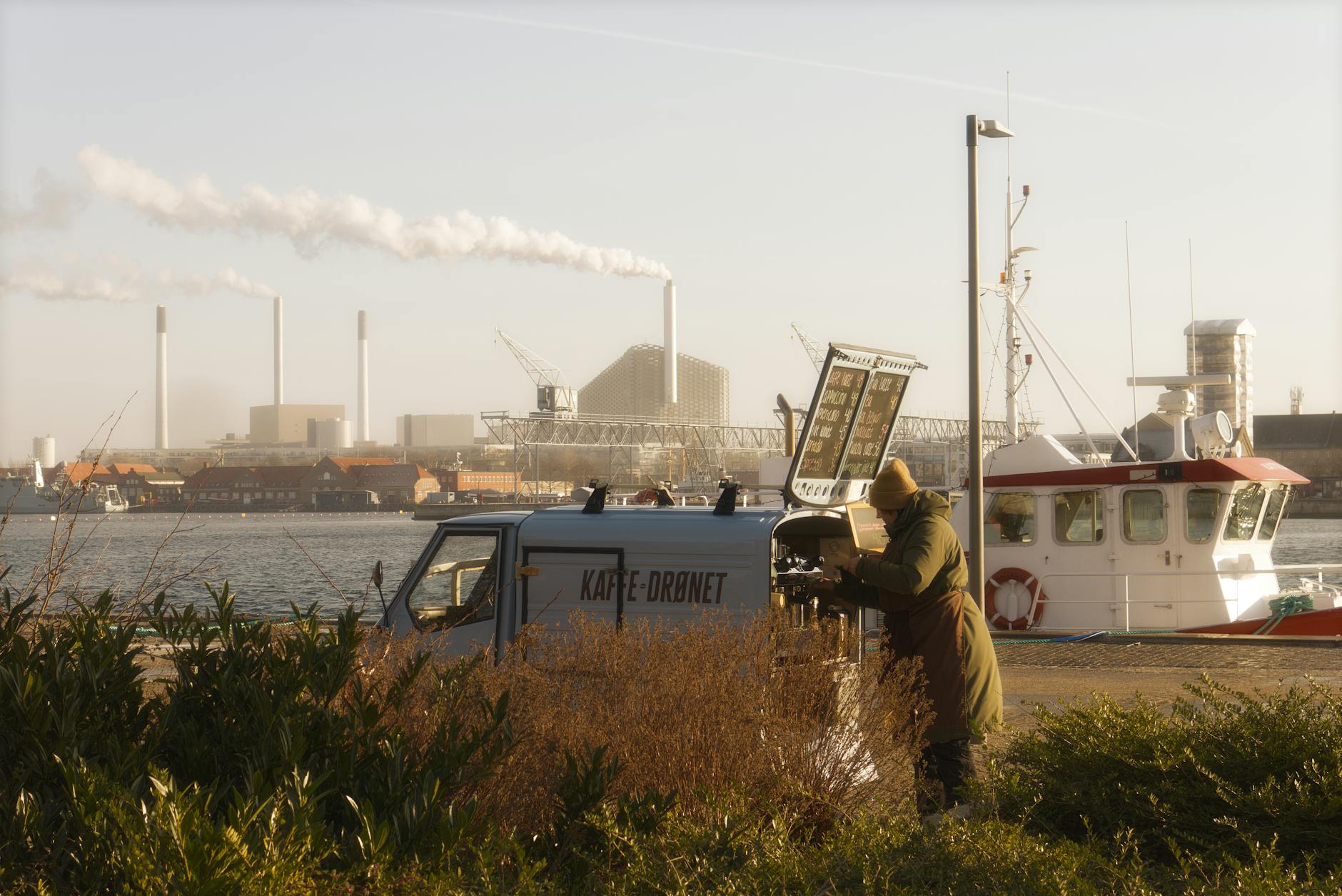 A serene view of a coffee van and harbor in Copenhagen, Denmark, during sunset.