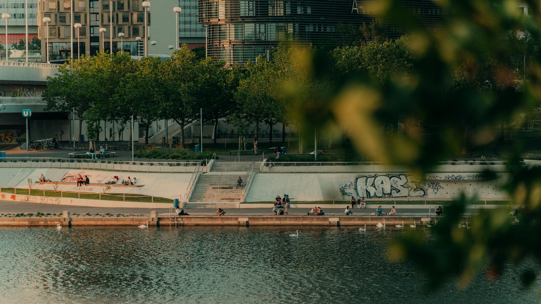 A picturesque riverside scene with people relaxing near a modern urban park.