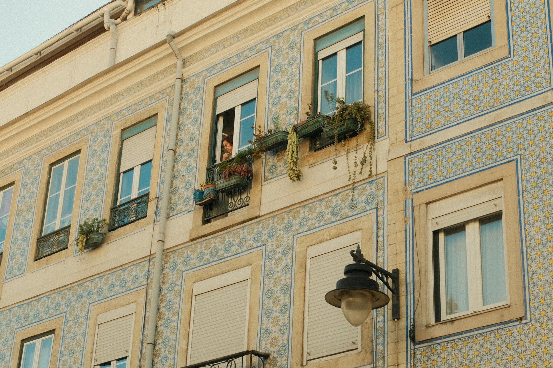 Historic Lisbon facade with azulejos tiles and a person looking out. Captures Portuguese architectural charm.